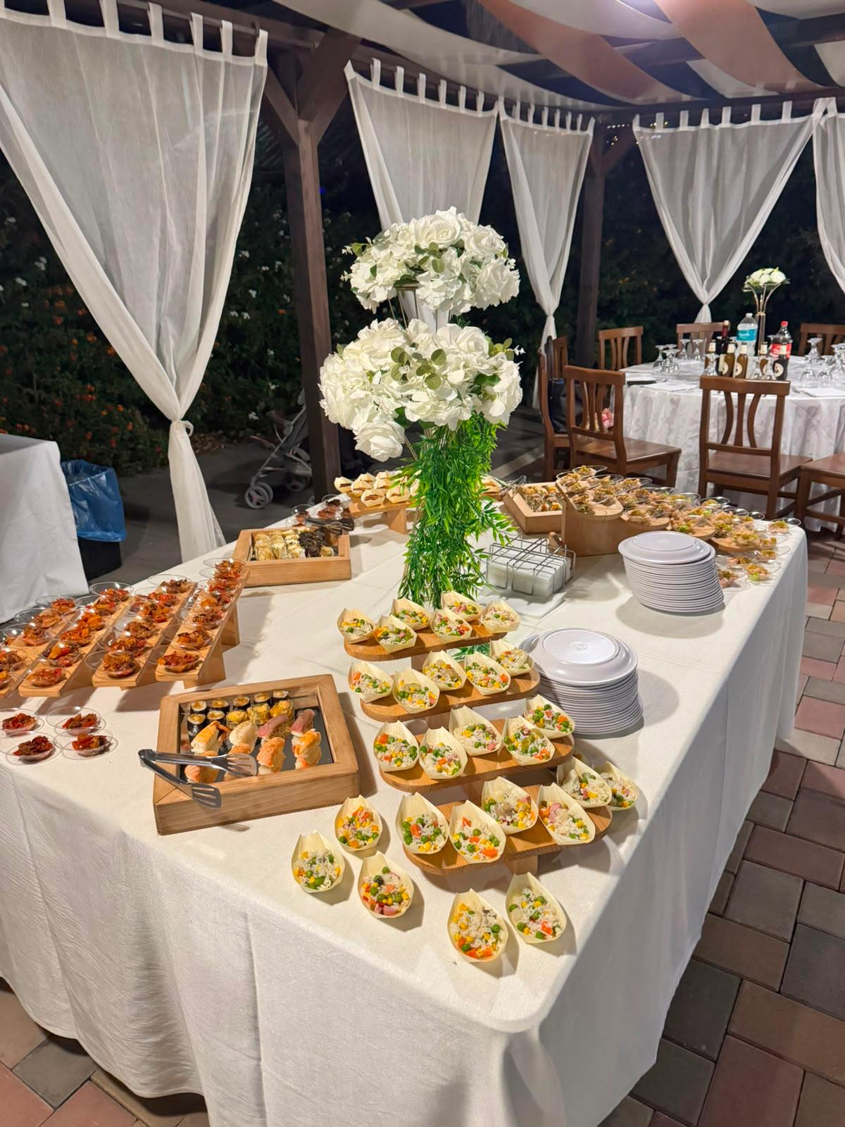 Il tavolo del buffet con crostatine, stuzzichini e fiori bianchi
