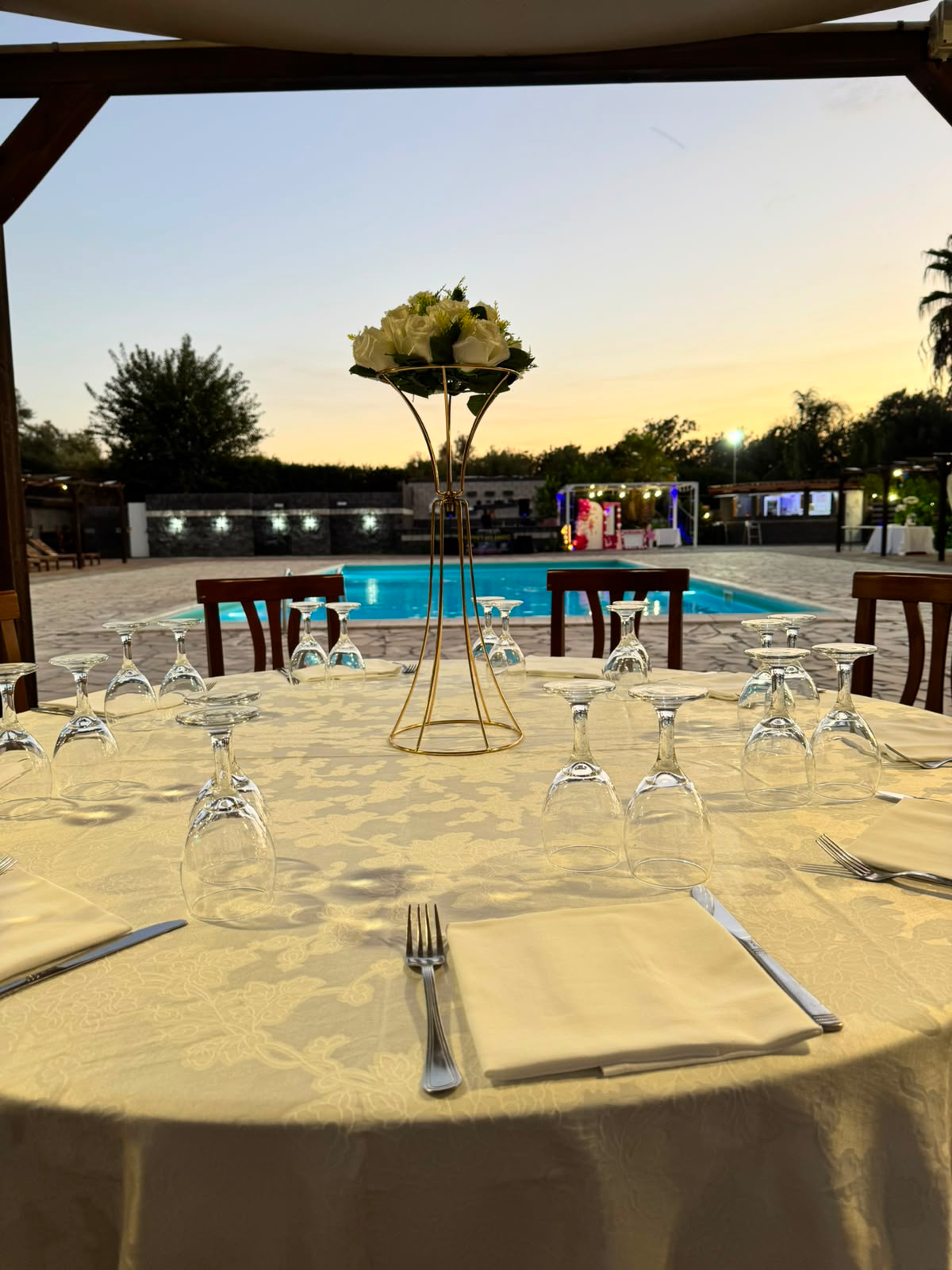 Tavolo apparecchiato a bordo piscina al tramonto